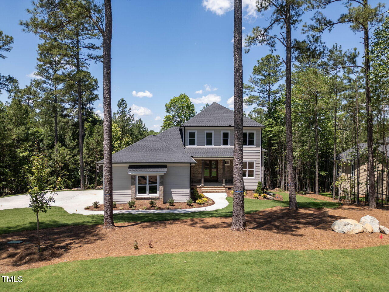 a front view of a house with garden and trees