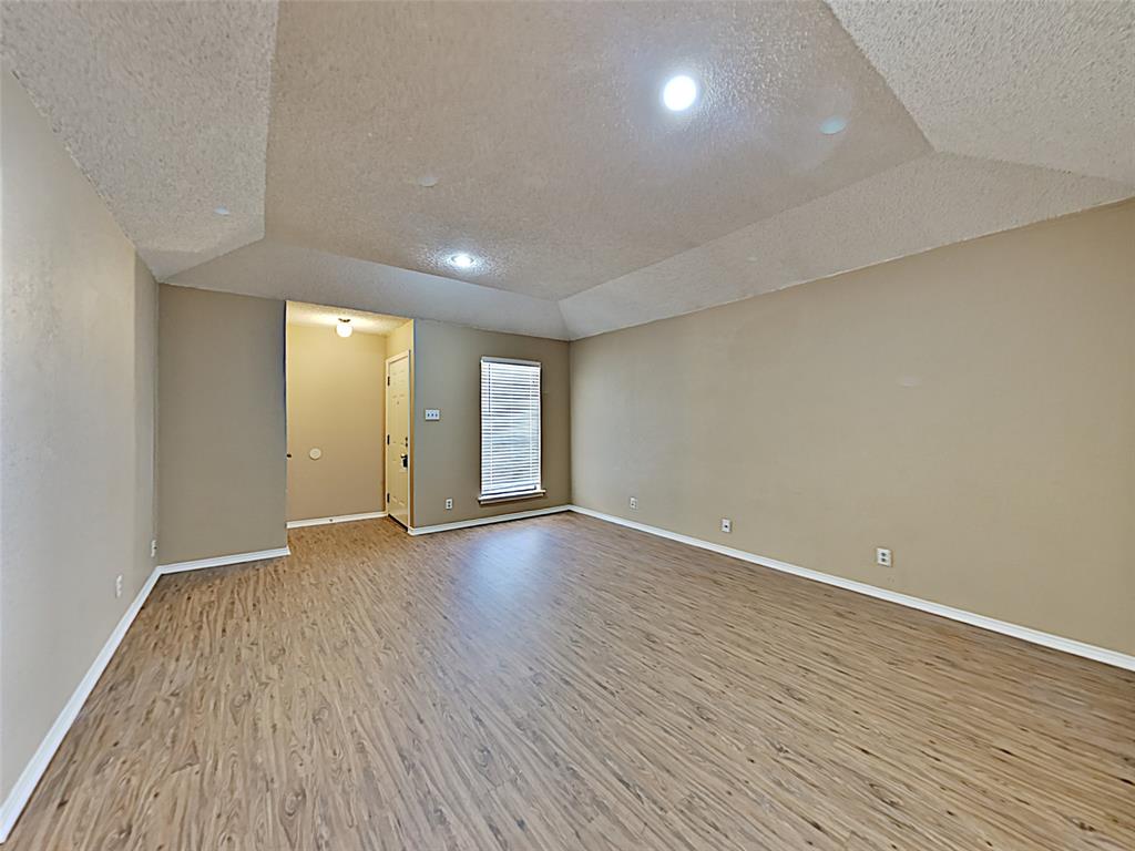 a view of an empty room with wooden floor and closet