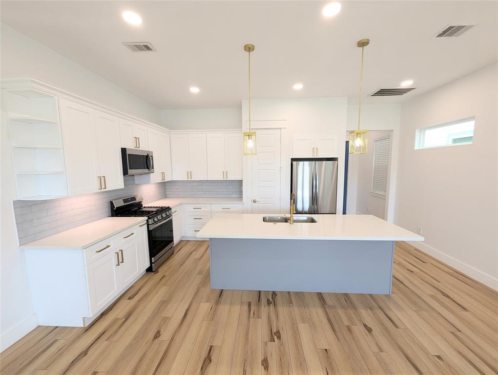 a large kitchen with kitchen island a white counter space stainless steel appliances and cabinets