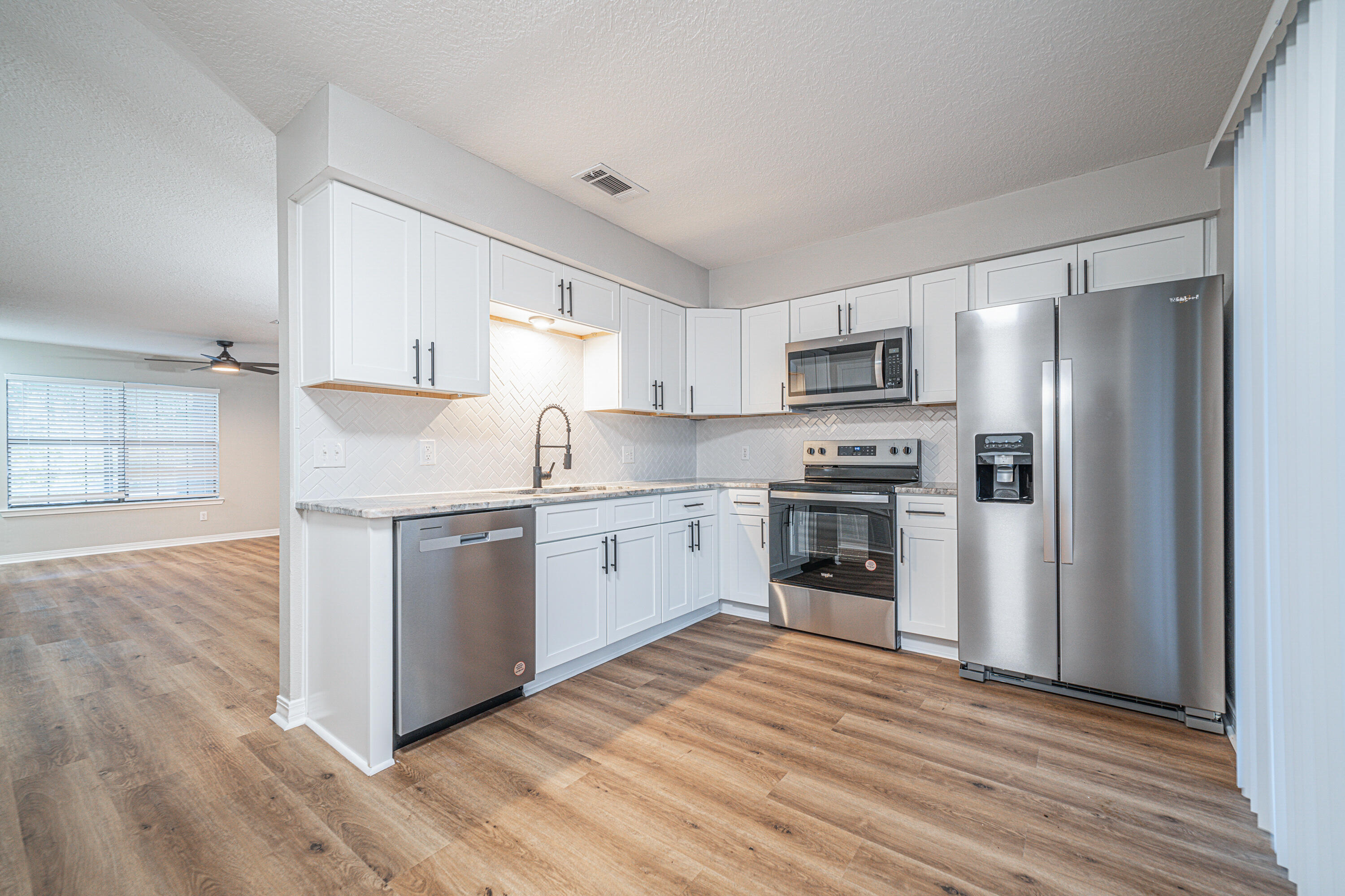 a kitchen with granite countertop white cabinets and stainless steel appliances