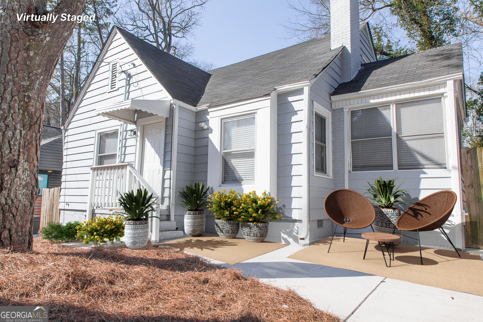 a backyard of a house with table and chairs and potted plants