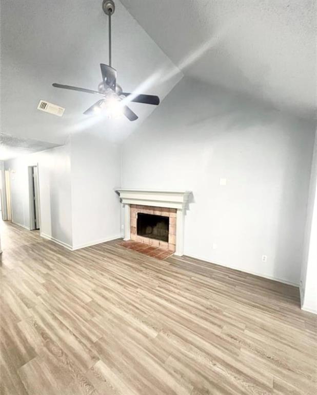 a view of an empty room with a fireplace and a ceiling fan