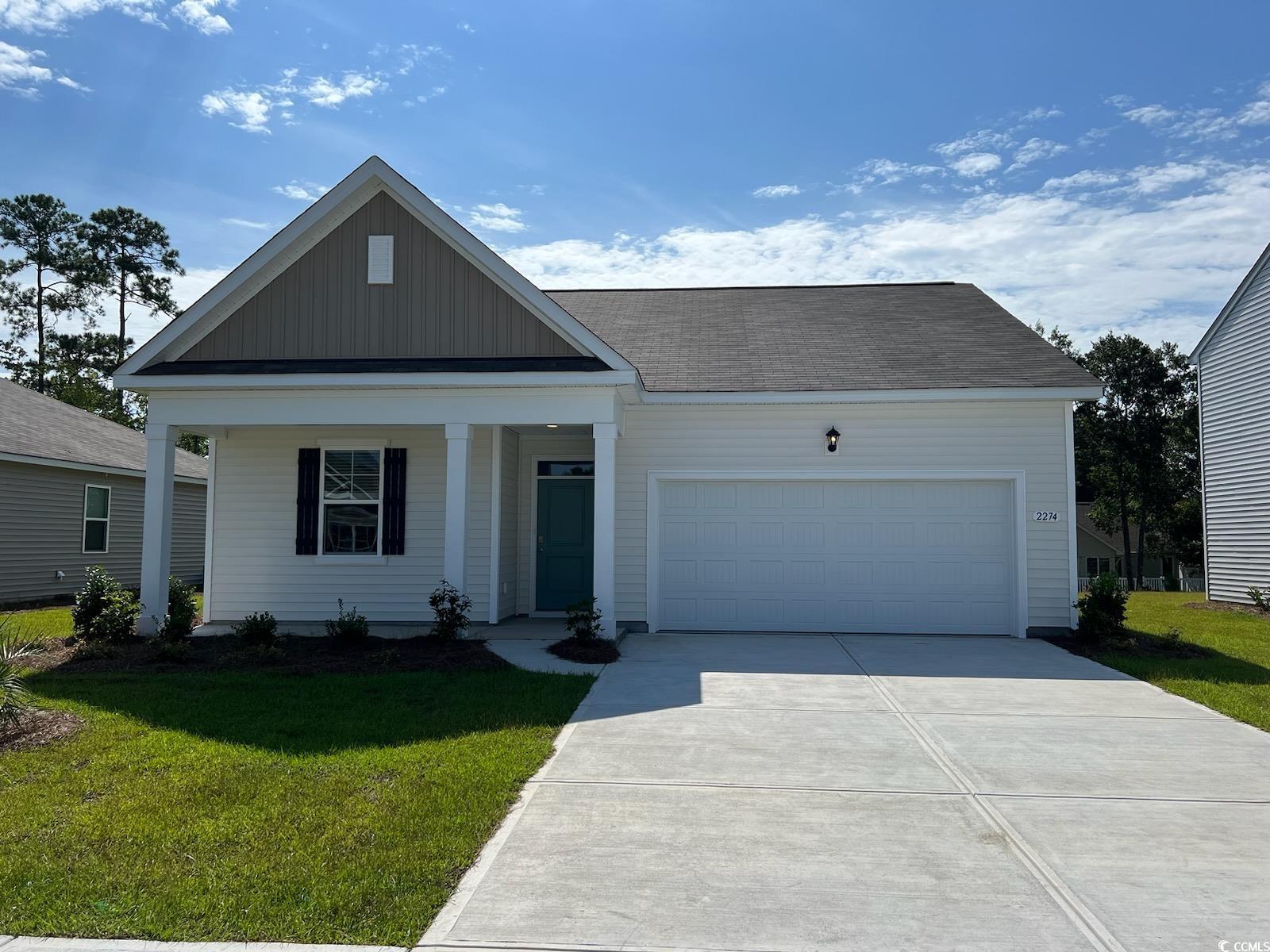 View of front facade featuring covered porch, a ga