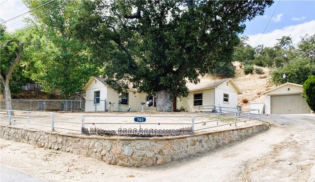 a view of a white house next to a yard with large trees