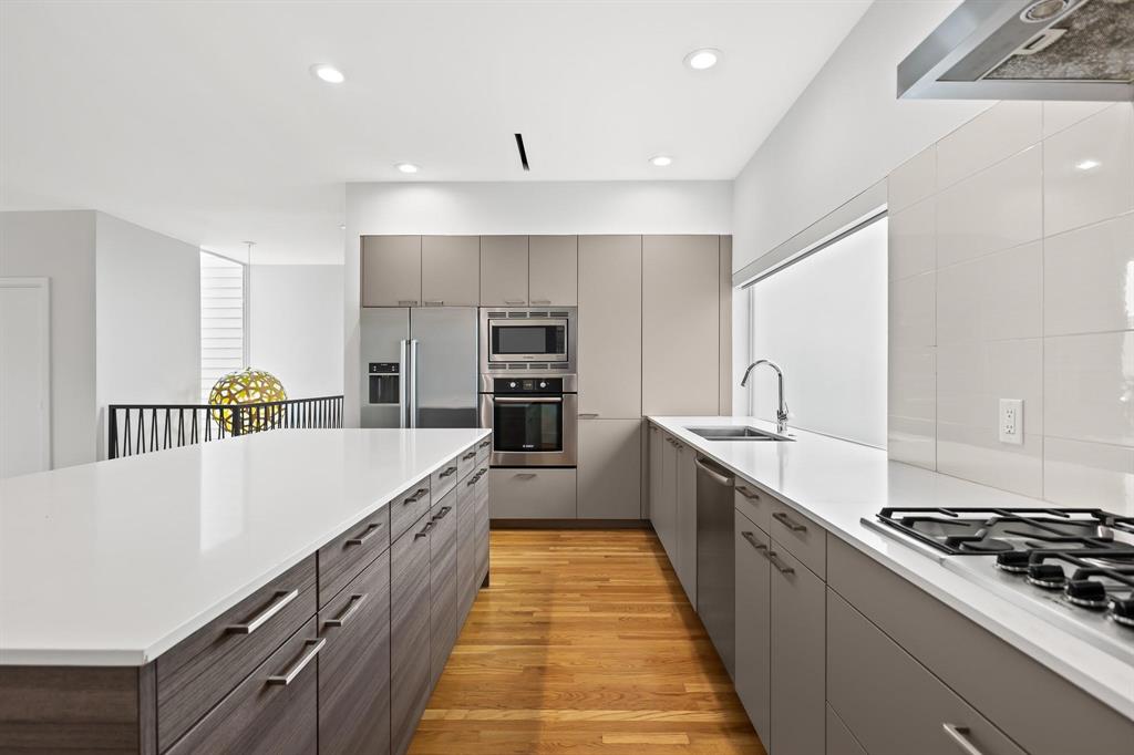 a large kitchen with stainless steel appliances granite countertop a lot of counter space and wooden floor