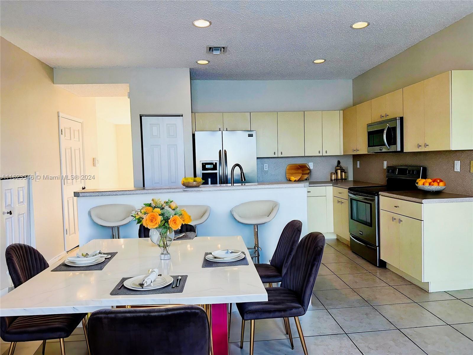 a kitchen with stainless steel appliances kitchen island granite countertop a sink a stove a table and chairs