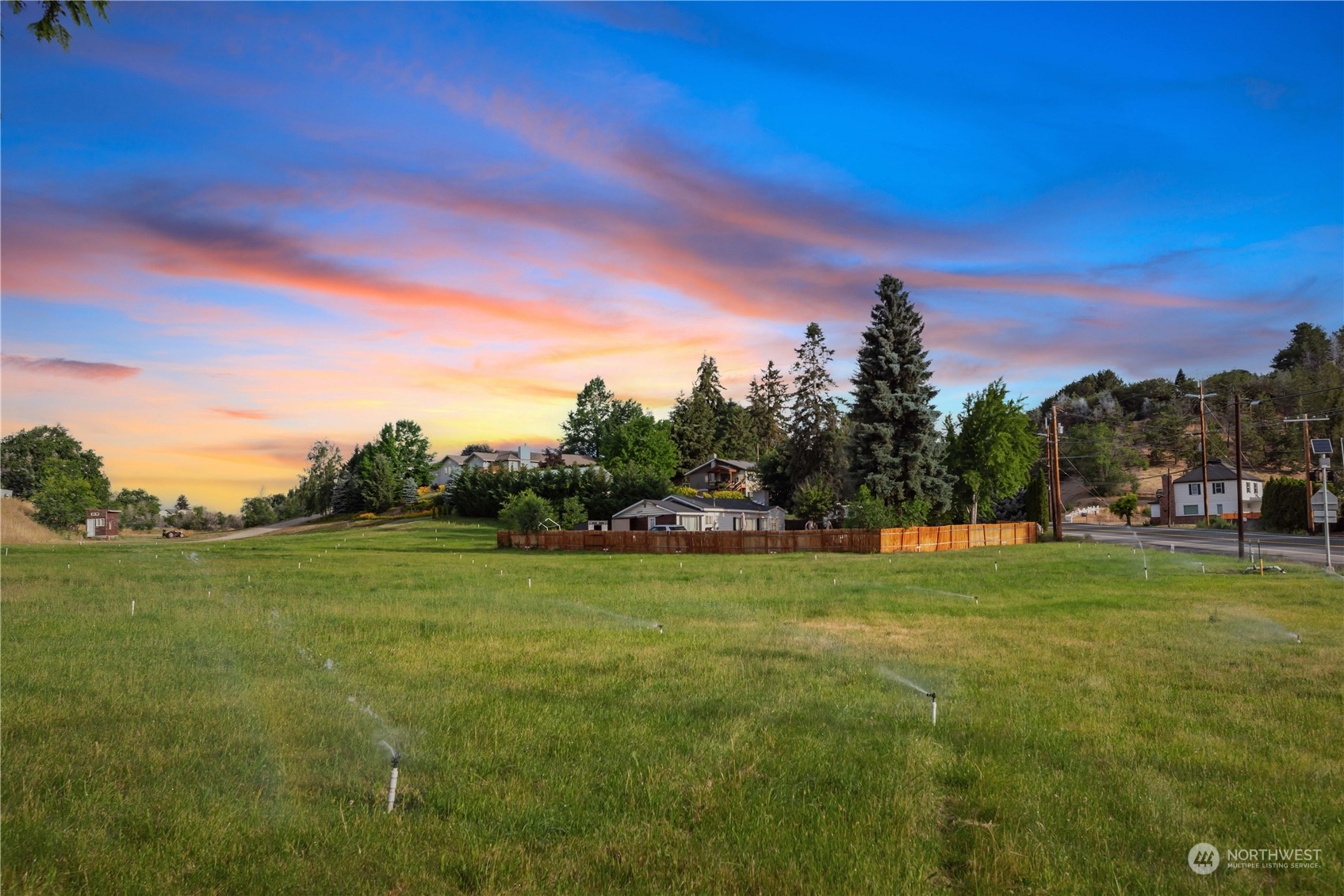 a view of a green field with sunset in the background