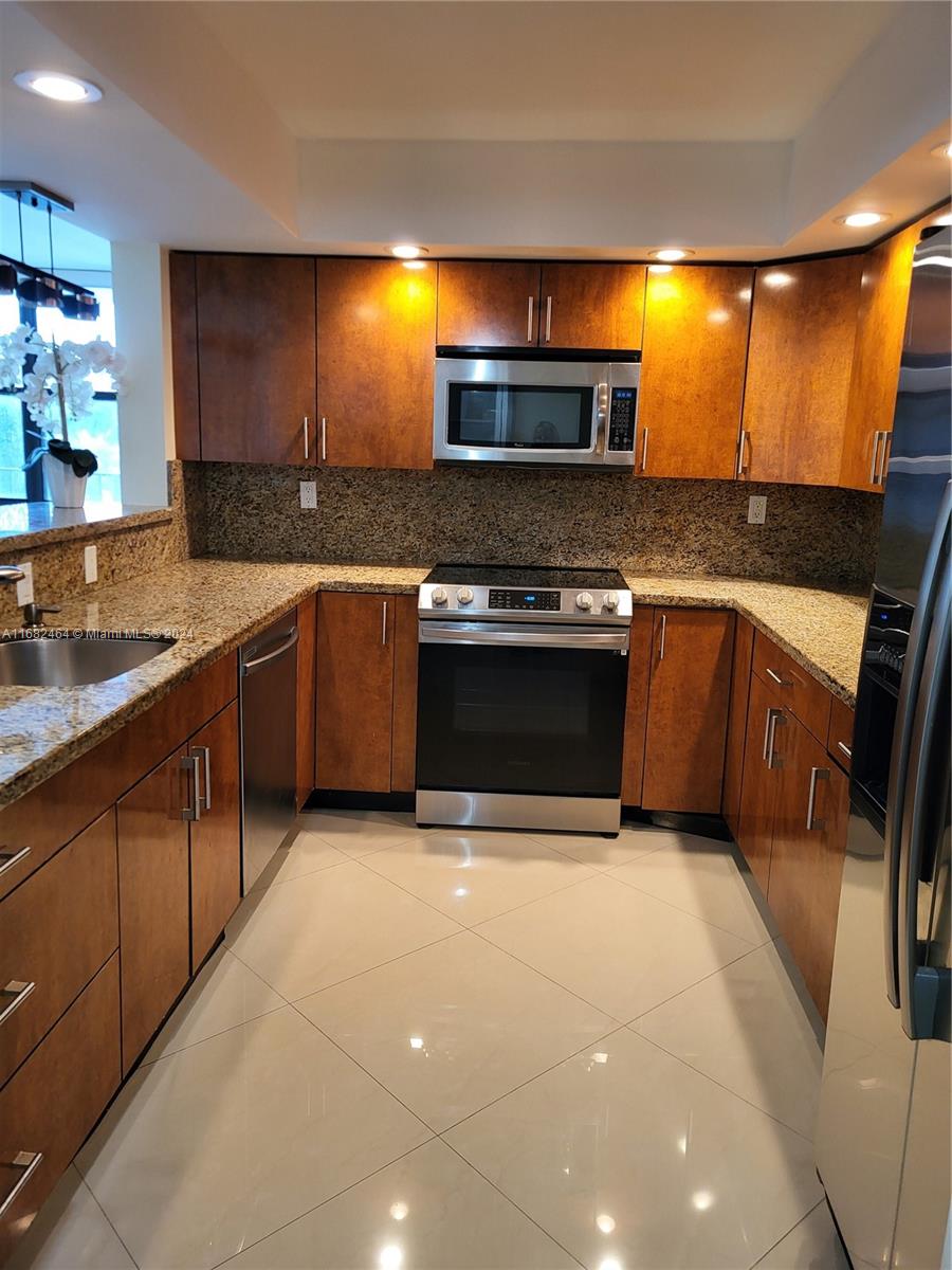 a kitchen with stainless steel appliances granite countertop a stove a sink and a microwave