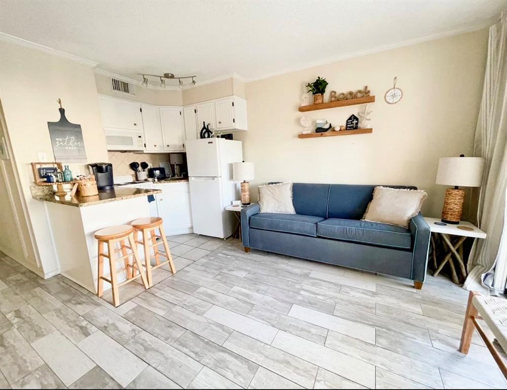 a living room with furniture and a dining table with kitchen appliances