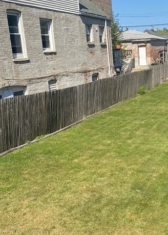 a view of a backyard with brick wall and wooden fence