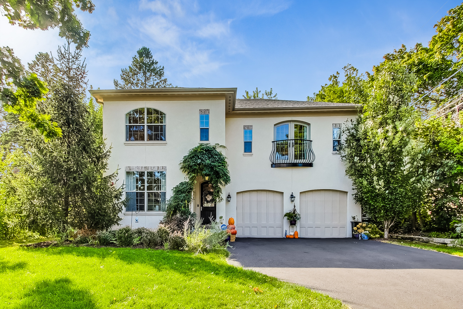 a view of a house with a yard plants and large tree