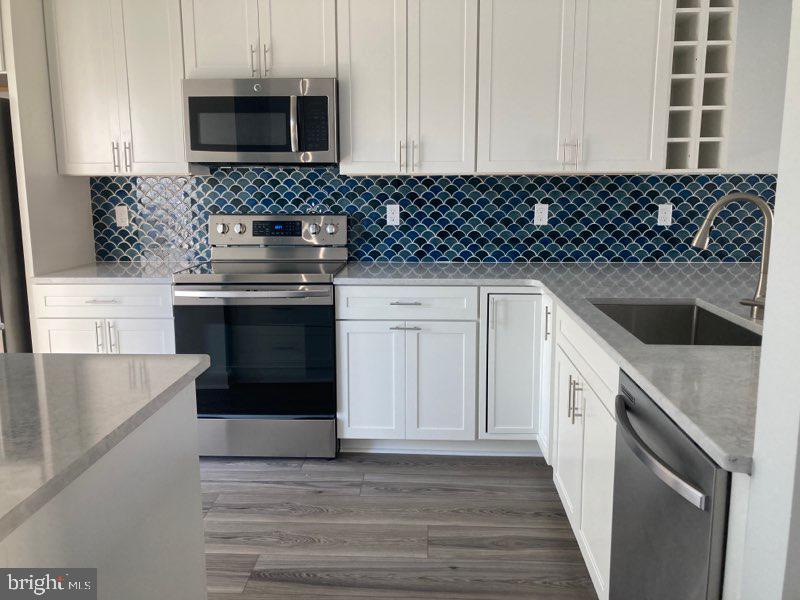 a kitchen with granite countertop white cabinets and black appliances