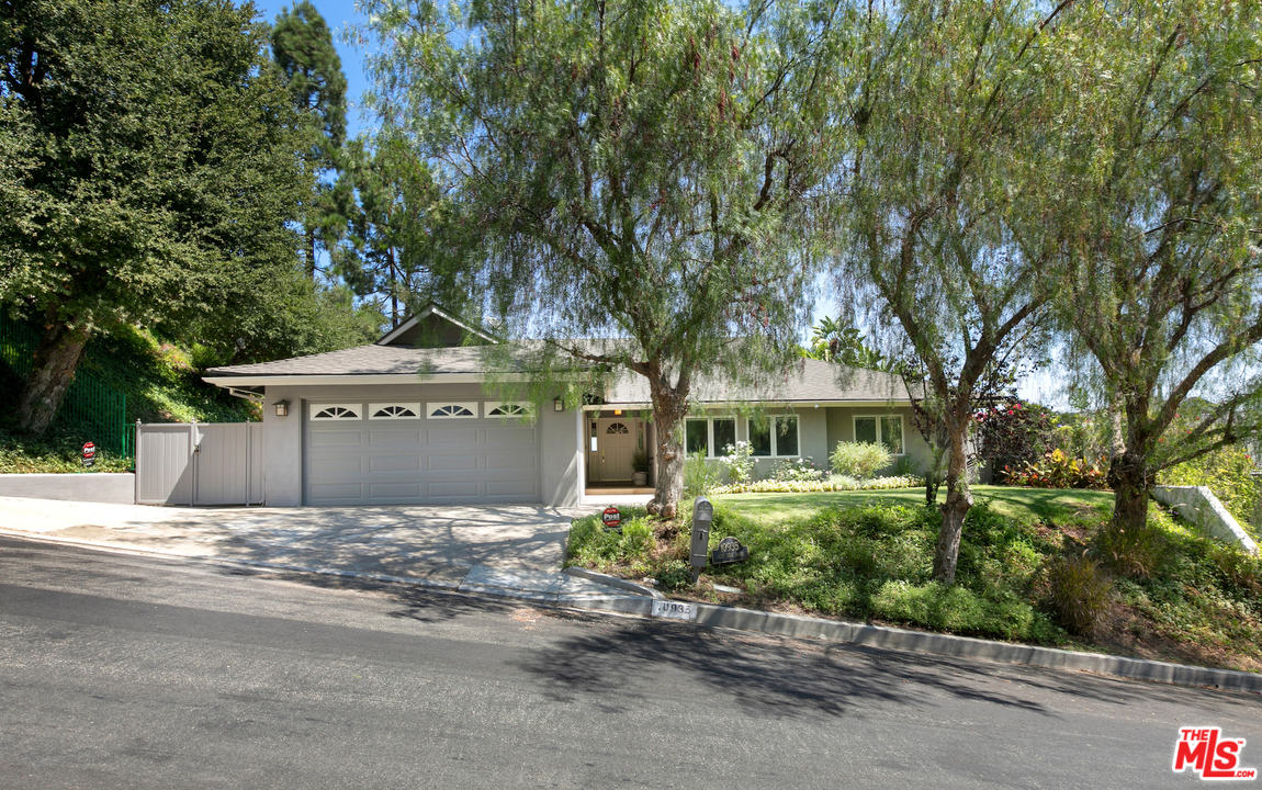 a front view of a house with a garden and tree