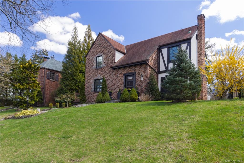 a view of a brick house with a big yard and large trees