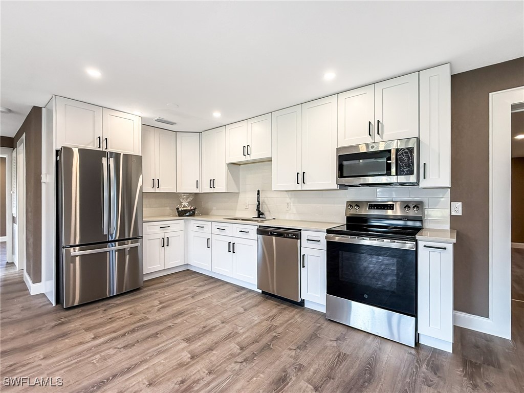 a kitchen with granite countertop a refrigerator stove and wooden cabinets