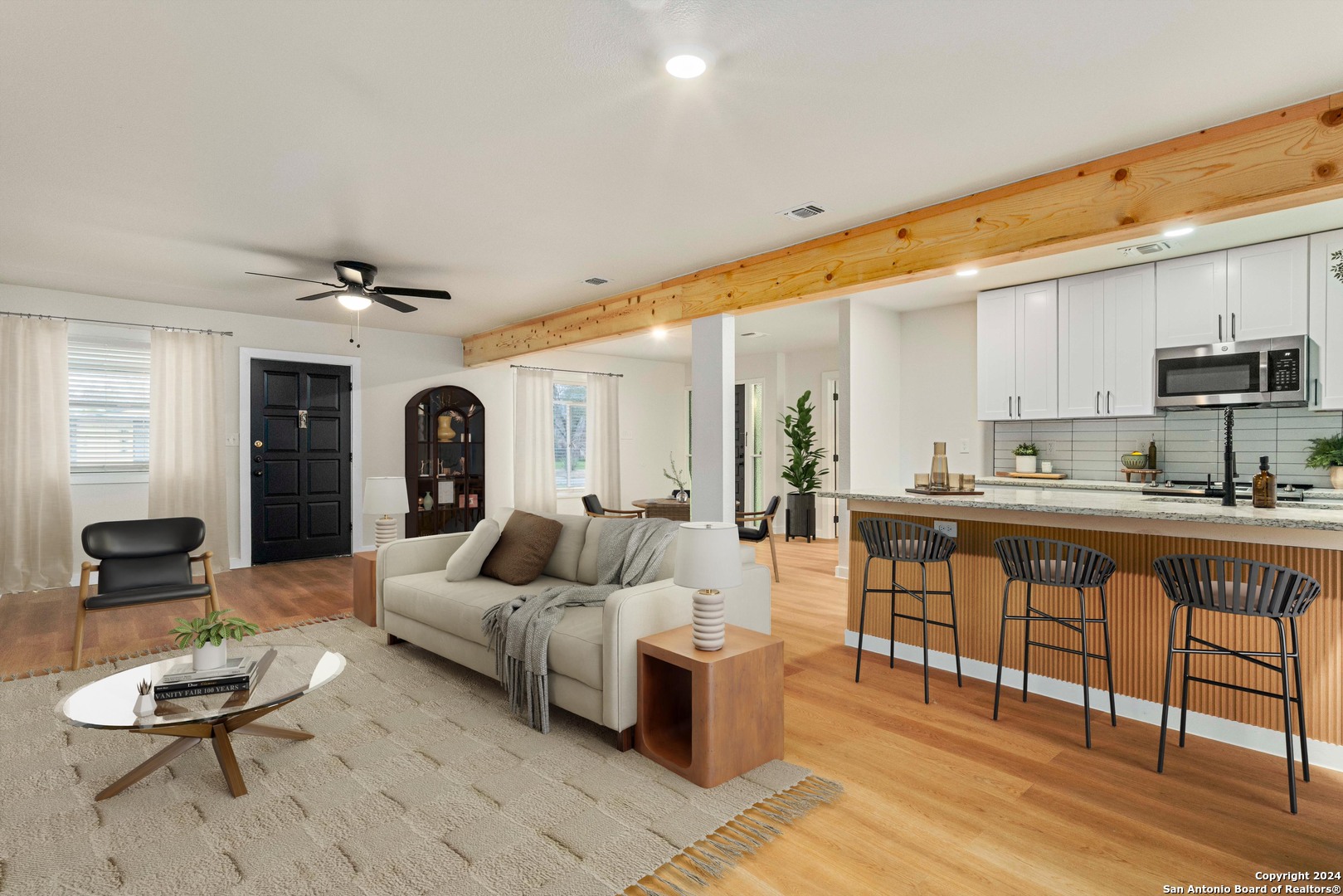 a living room with furniture a rug kitchen view and a large window