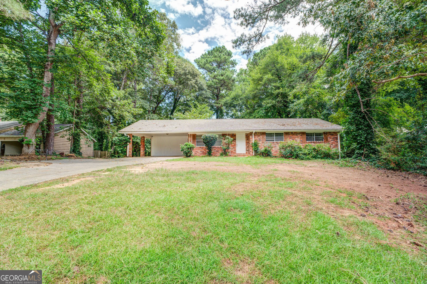 a front view of house with yard and trees in the background