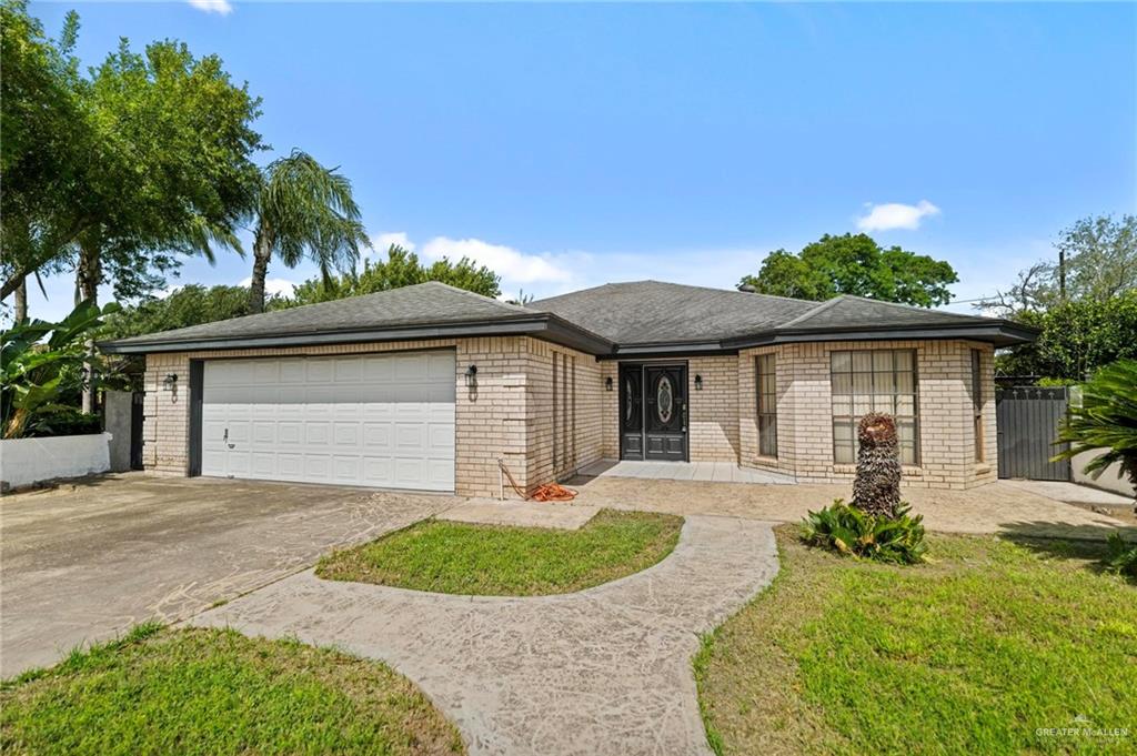 Ranch-style home featuring a garage and a front lawn