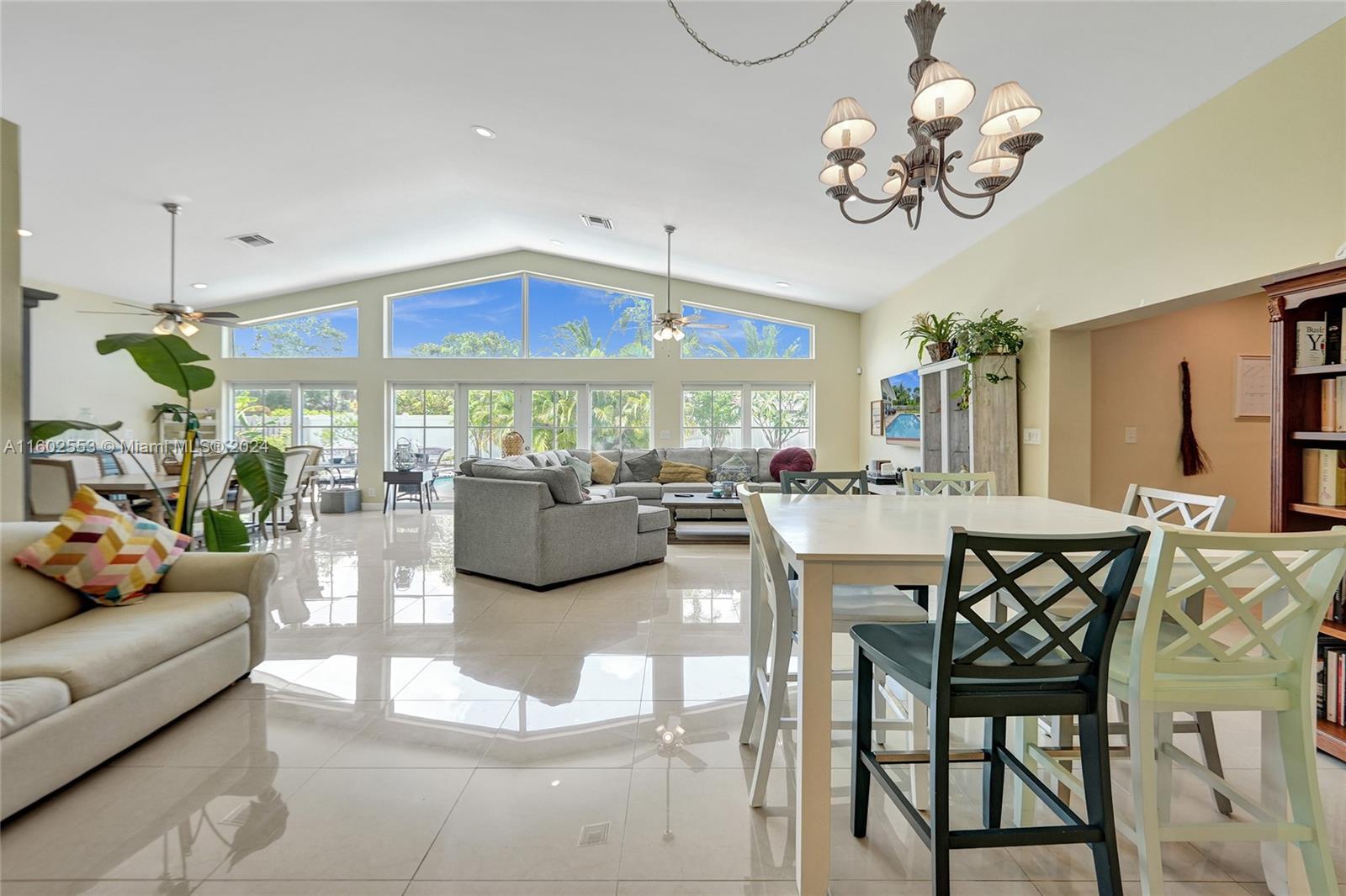 a view of a dining room with furniture a chandelier and large windows