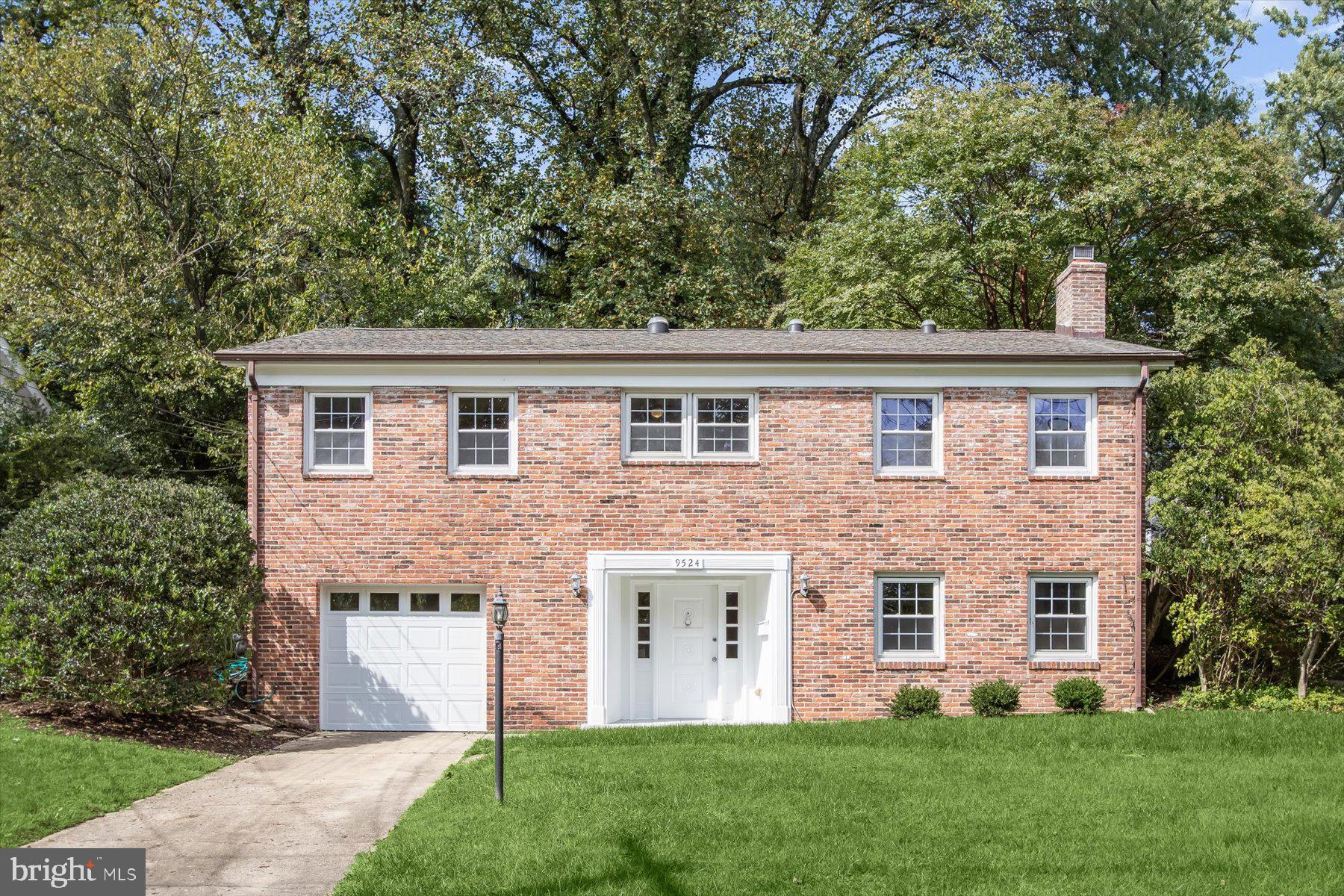 a front view of a house with a yard and trees