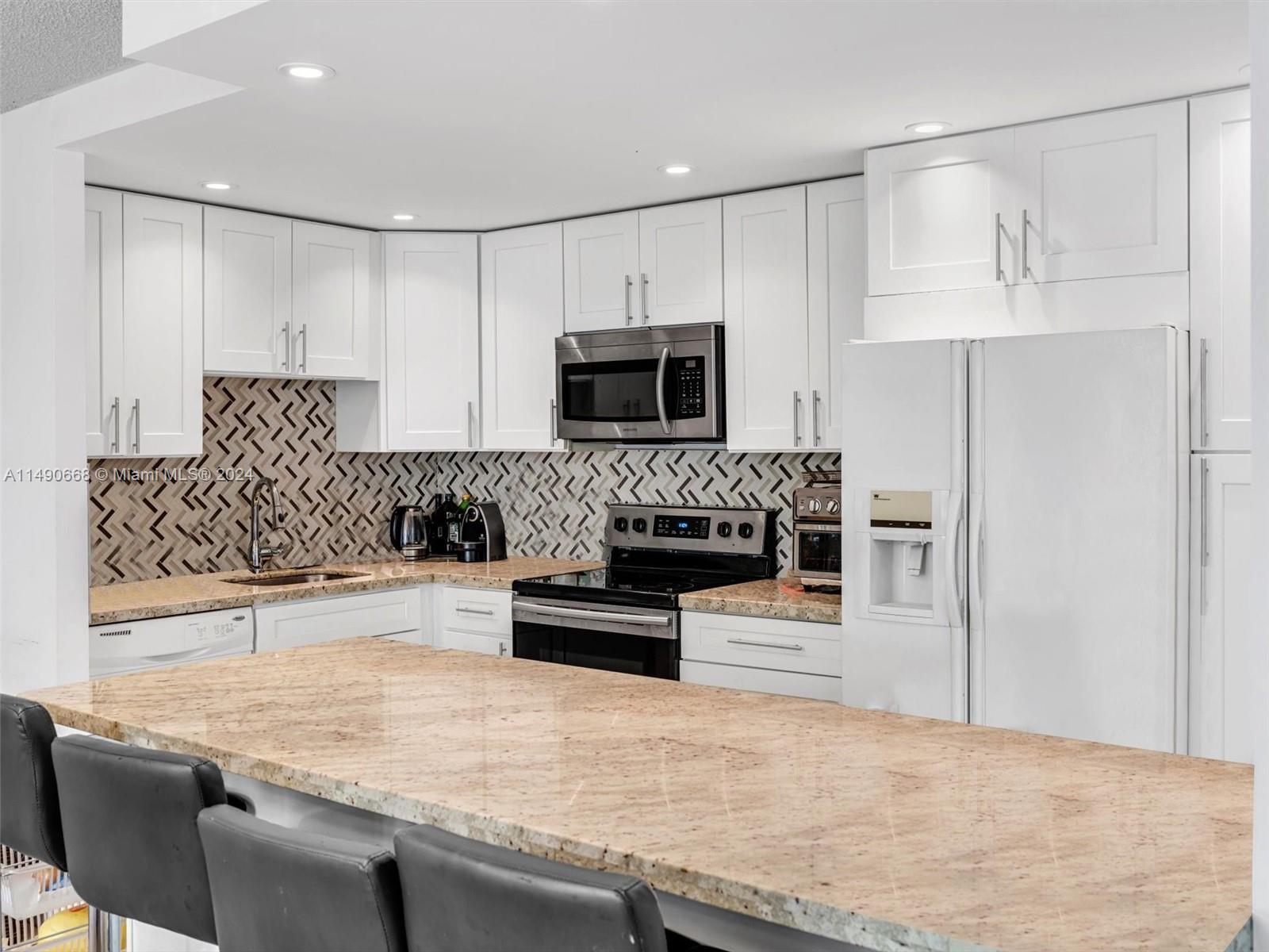 a kitchen with granite countertop a stove a sink and a microwave