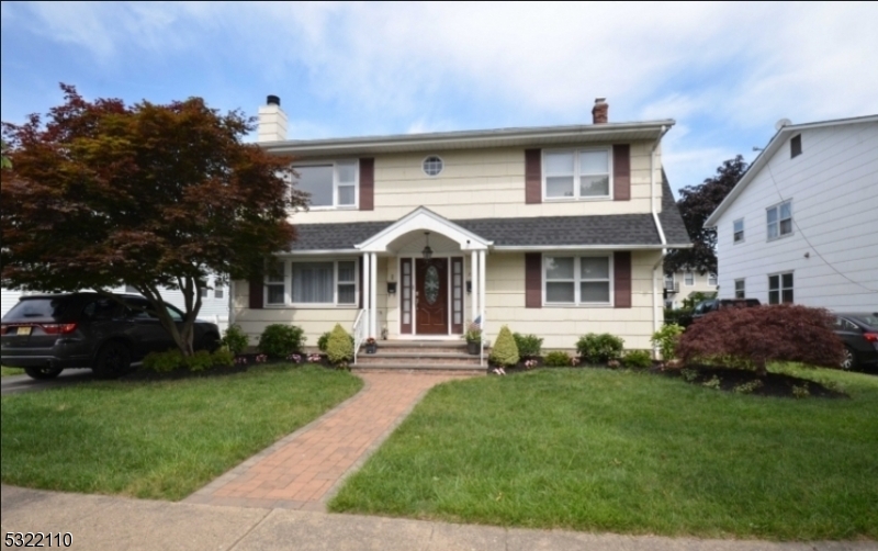 a front view of a house with a garden and trees