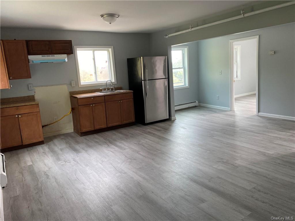 Kitchen with stainless steel refrigerator, light hardwood / wood-style flooring, plenty of natural light, and range hood