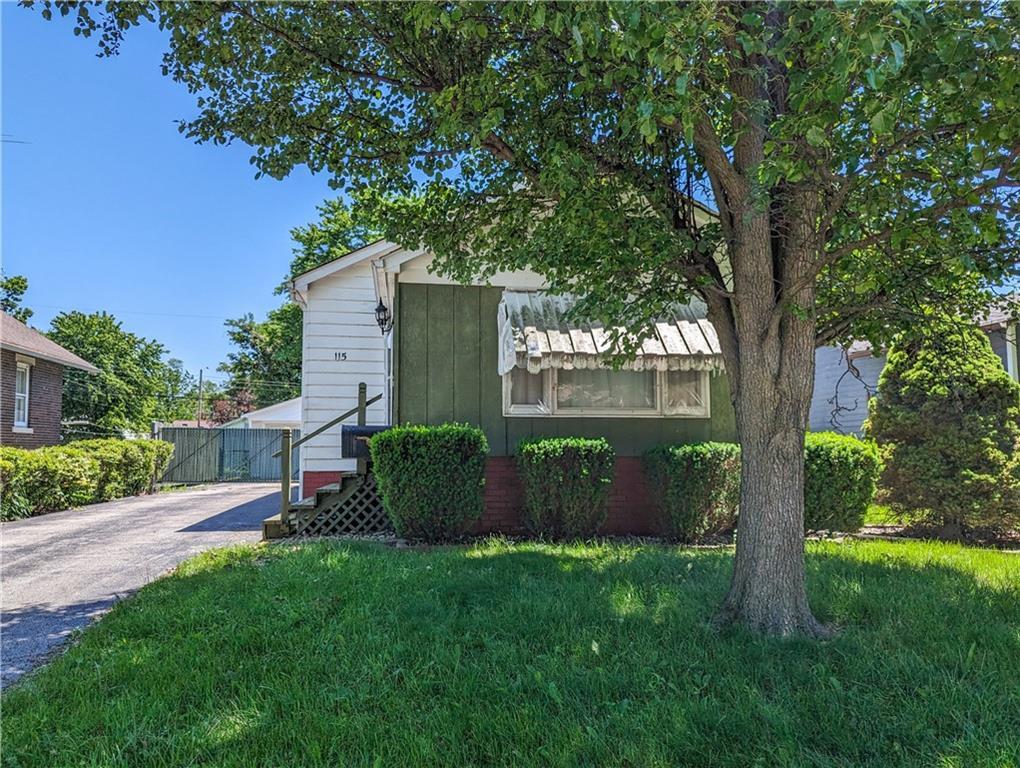 a view of a house with a yard and a large tree