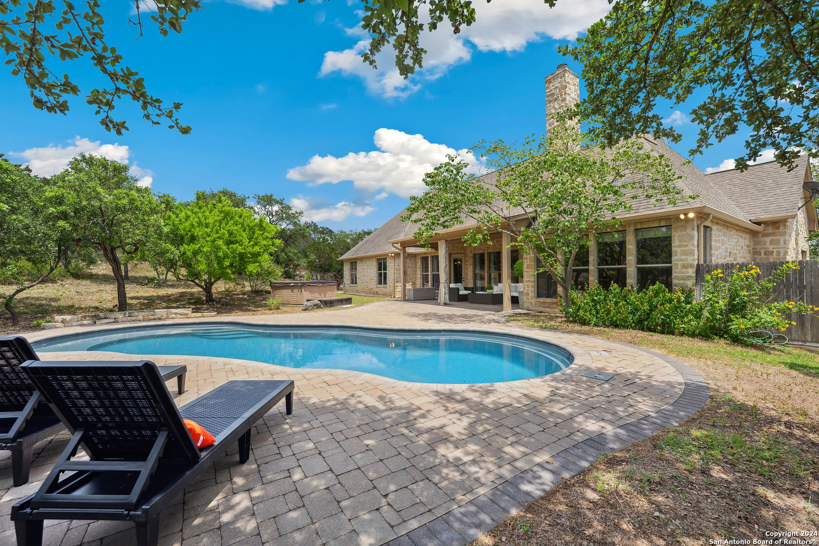 a view of swimming pool with lawn chairs and plants