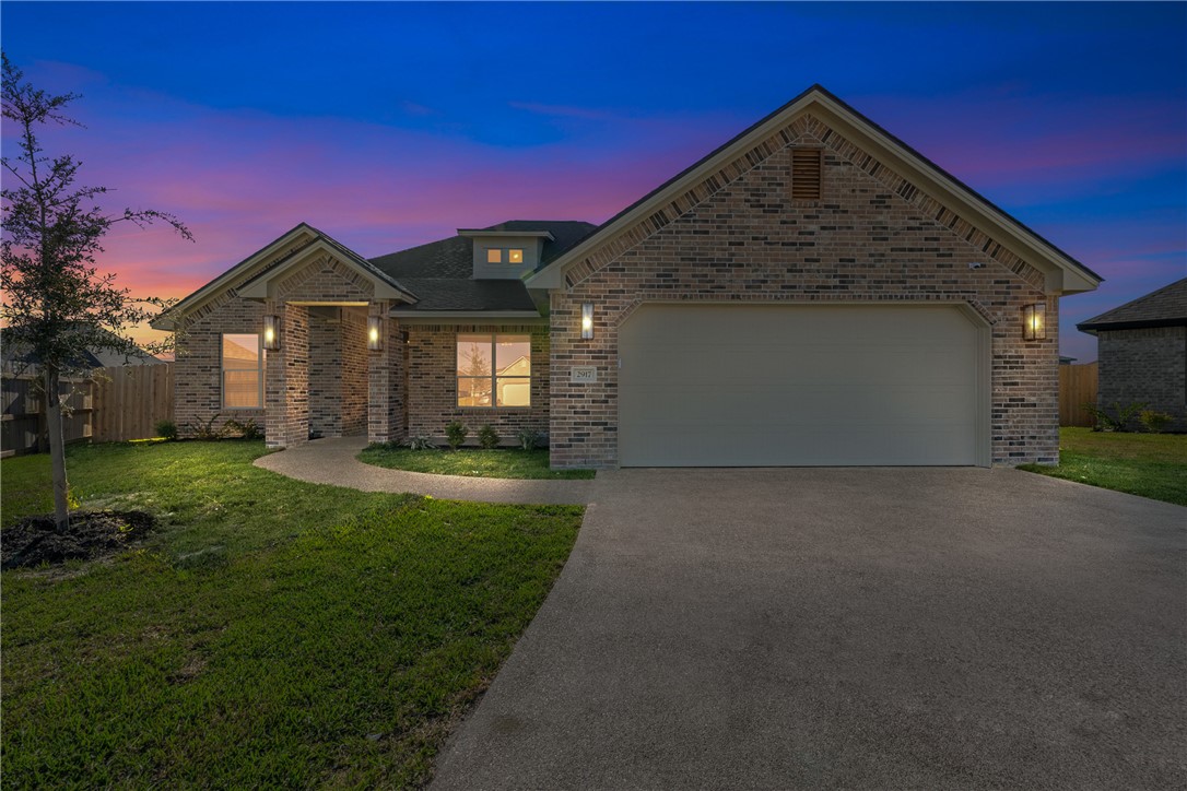 View of front of property with a yard and a garage