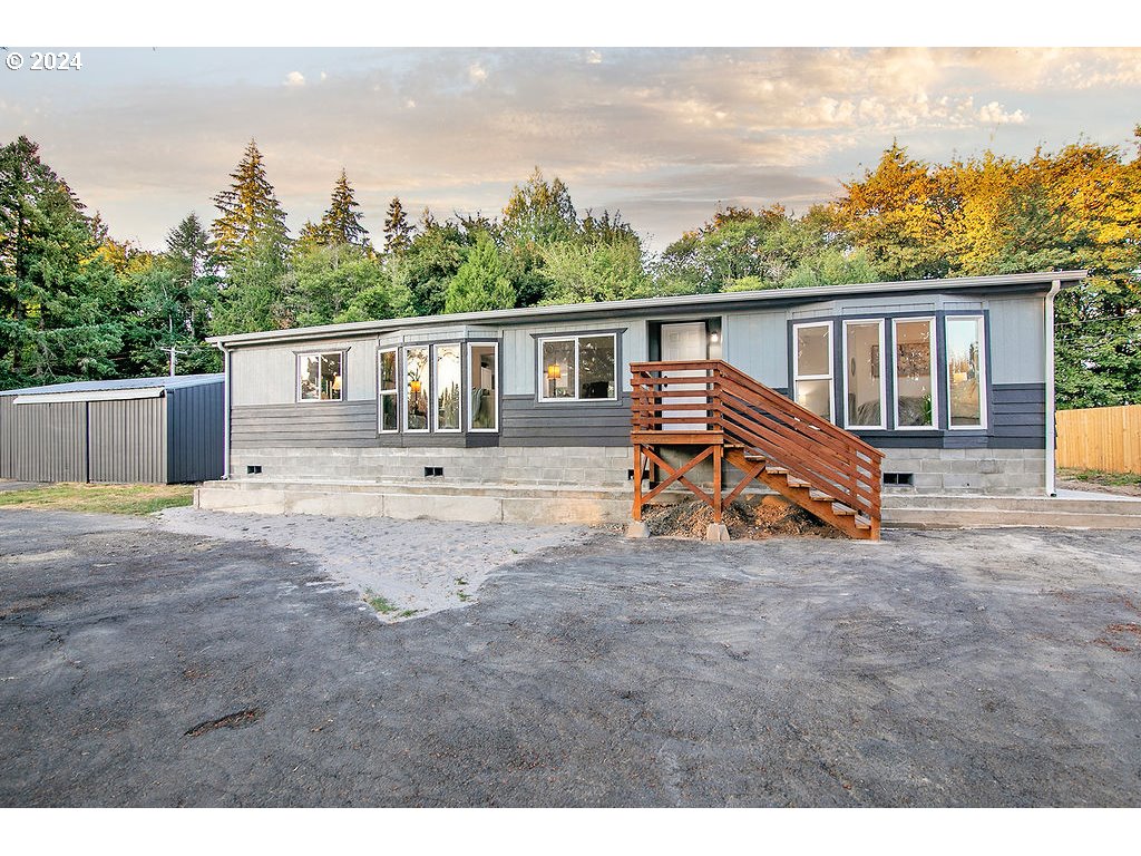 a view of a house with backyard and trees in the background