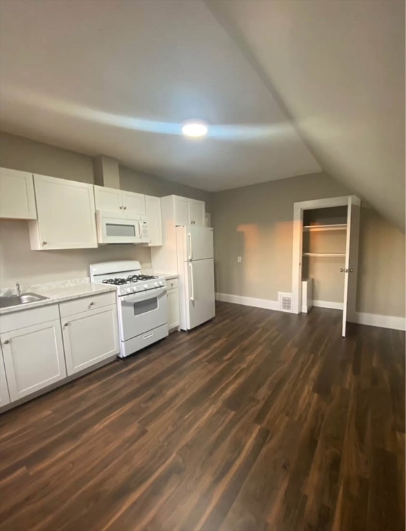 a kitchen with granite countertop white cabinets and white appliances