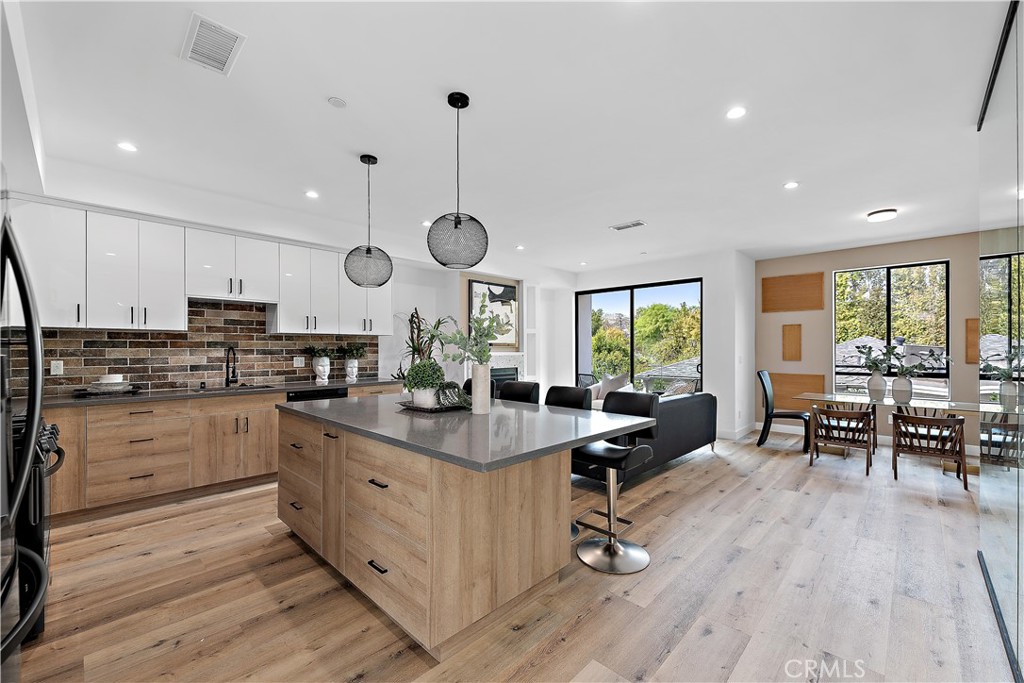 an open kitchen with wooden floor and stainless steel appliances