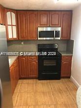 a kitchen with granite countertop a stove top oven microwave and refrigerator