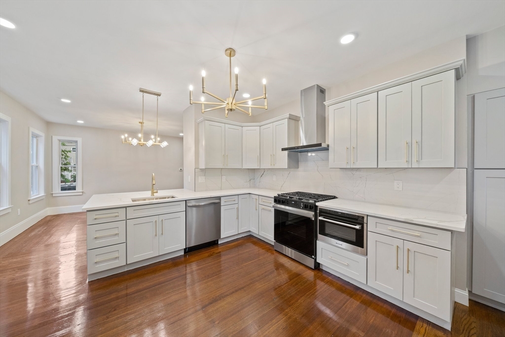 a large kitchen with stainless steel appliances granite countertop a stove and a wooden floors