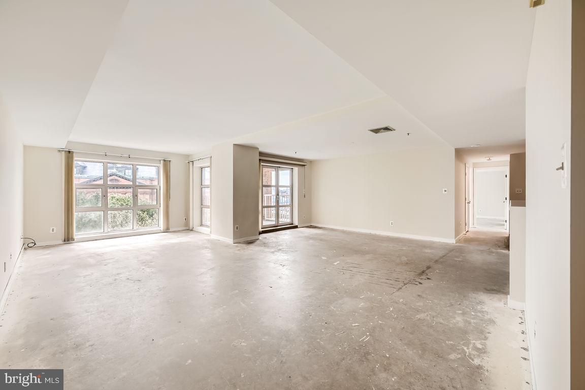 an empty room with windows and ceiling fan