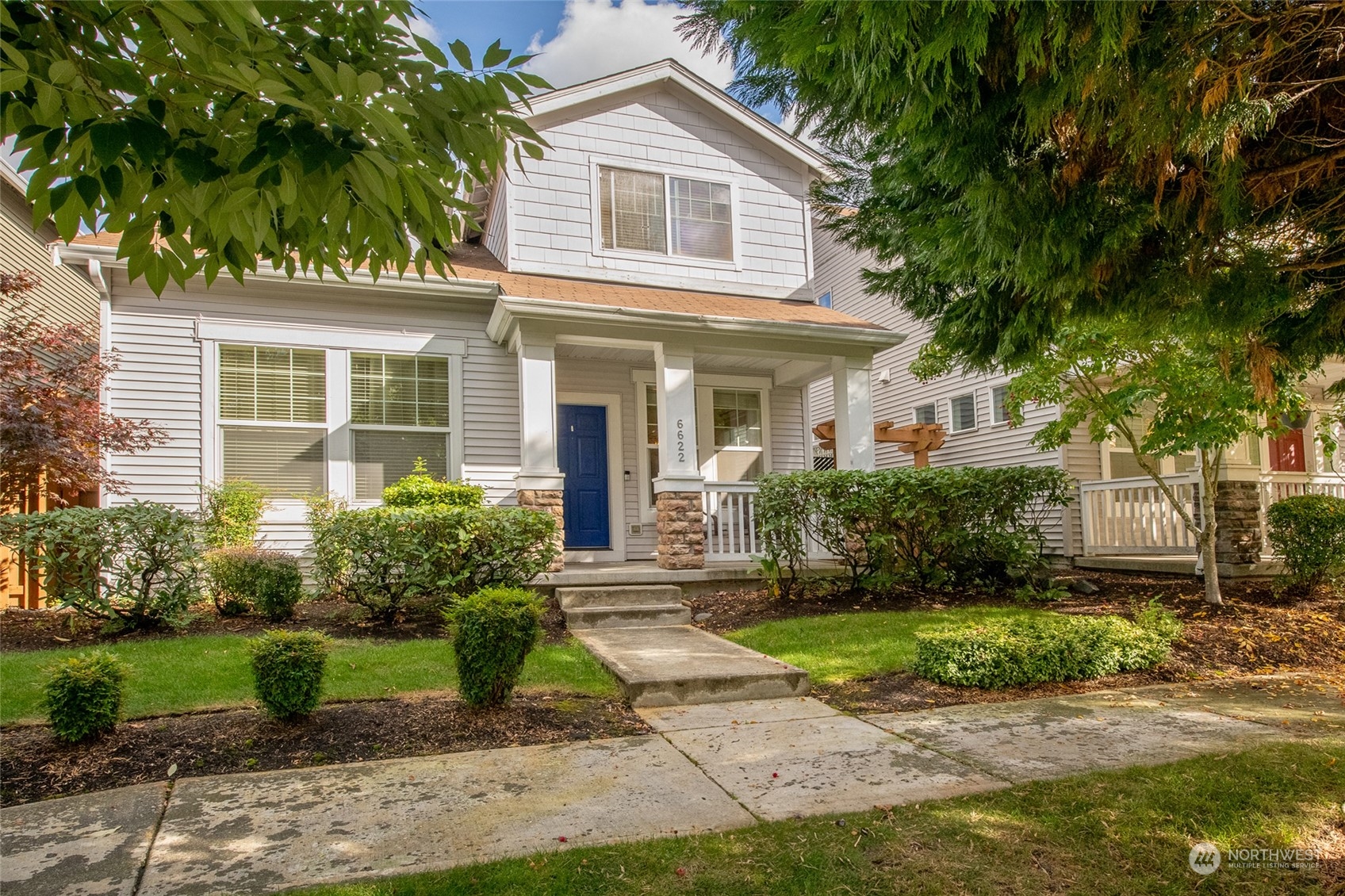 a front view of a house with a yard and potted plants