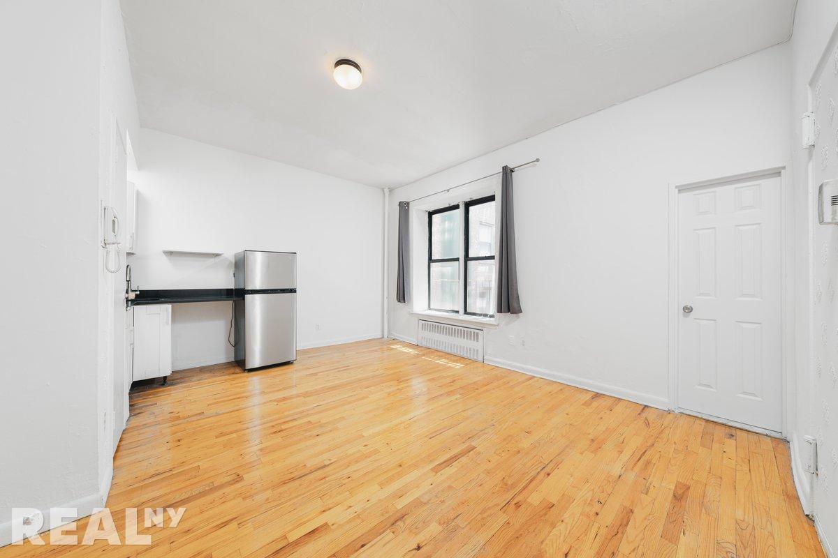 a view of empty room with wooden floor and cabinet