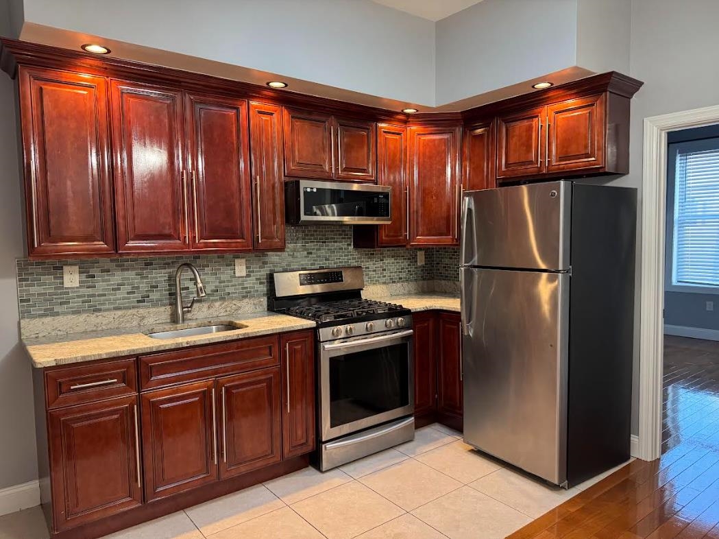 a kitchen with stainless steel appliances granite countertop a refrigerator and a stove top oven