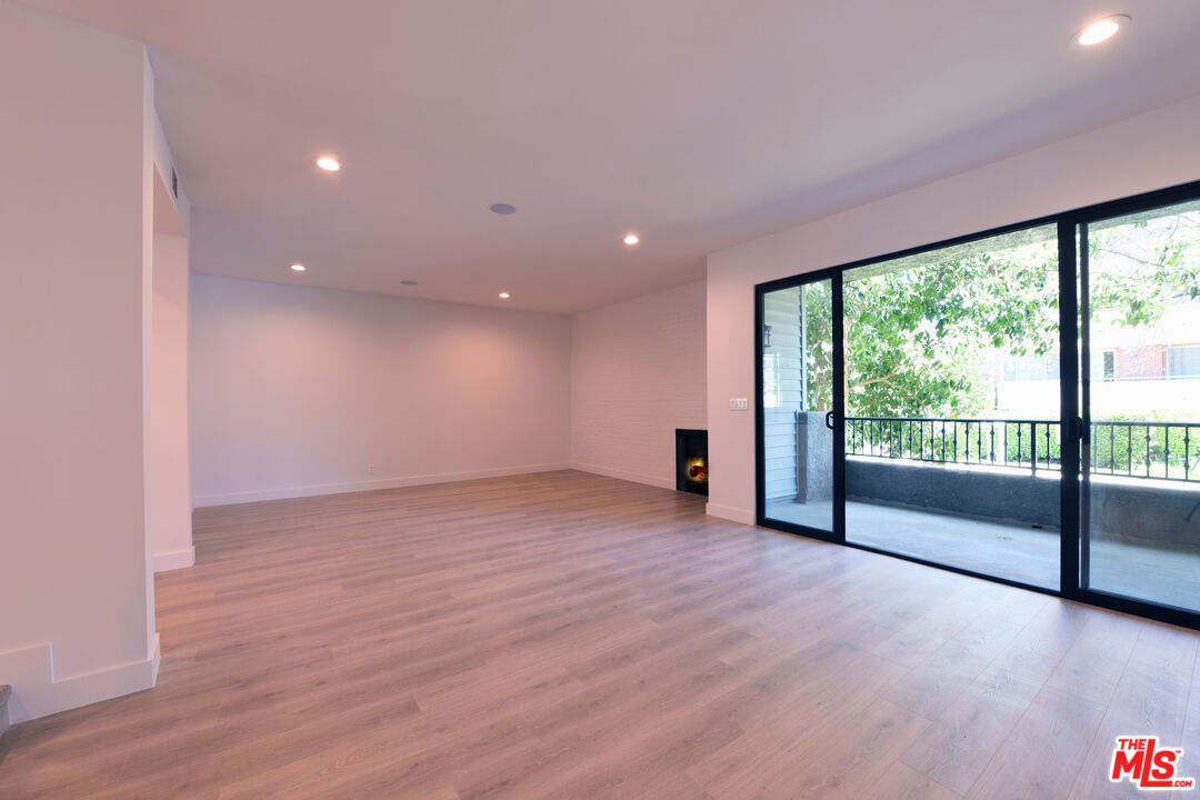 a view of an empty room with wooden floor and a floor to ceiling window