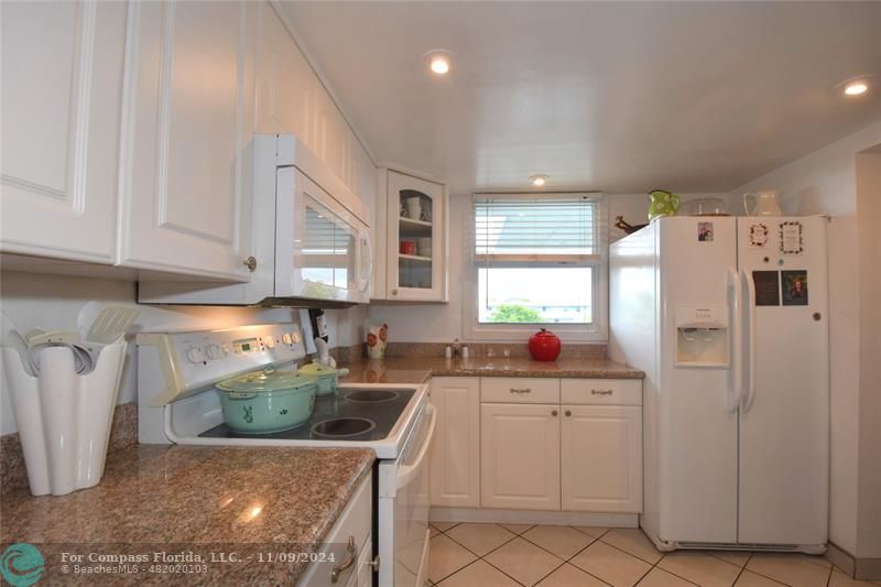 a kitchen with white cabinets a sink a window and stainless steel appliances