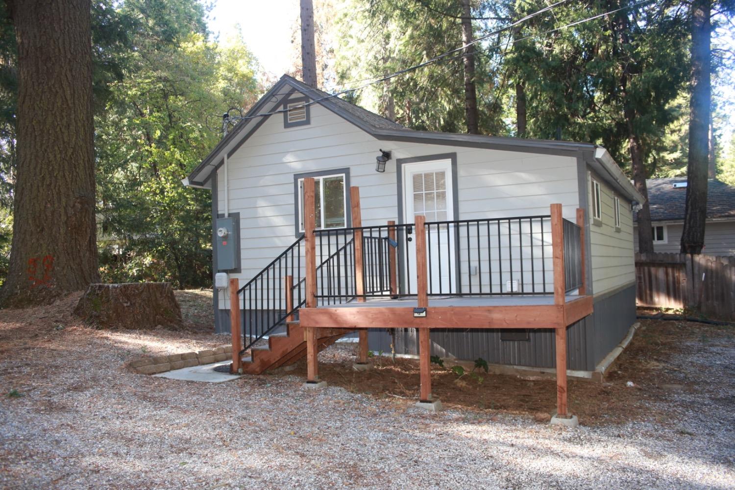 a view of a house with a yard and deck area under a large tree