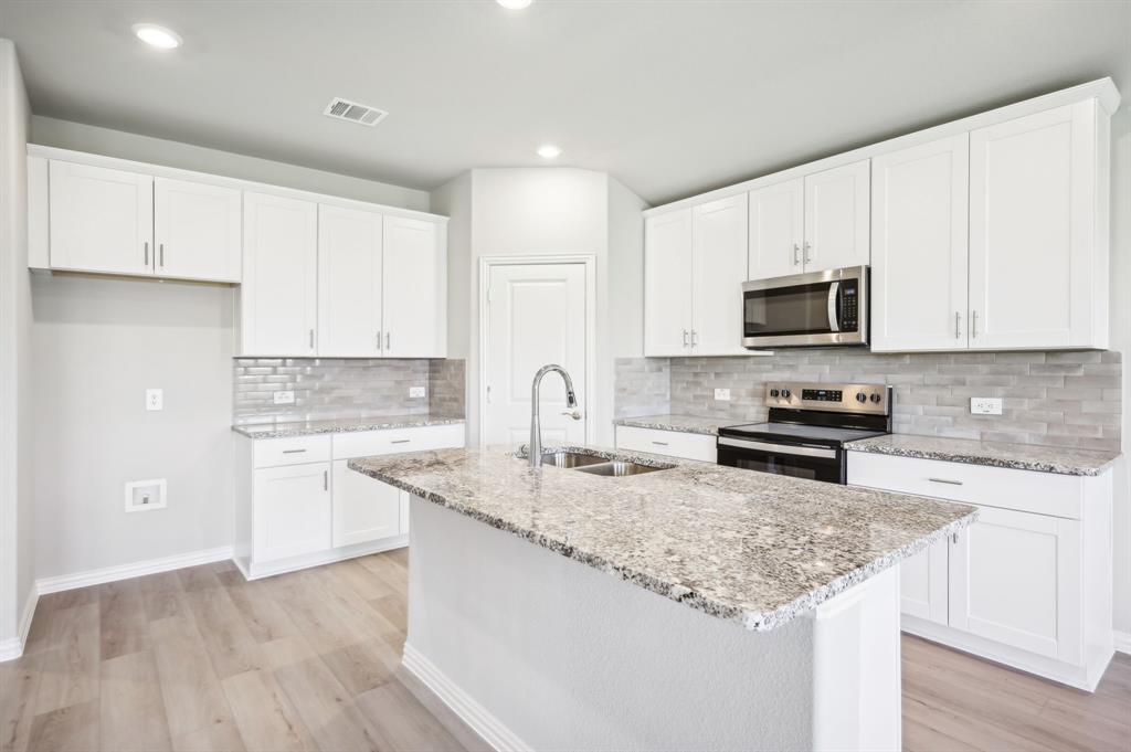 a kitchen with granite countertop white cabinets and a sink