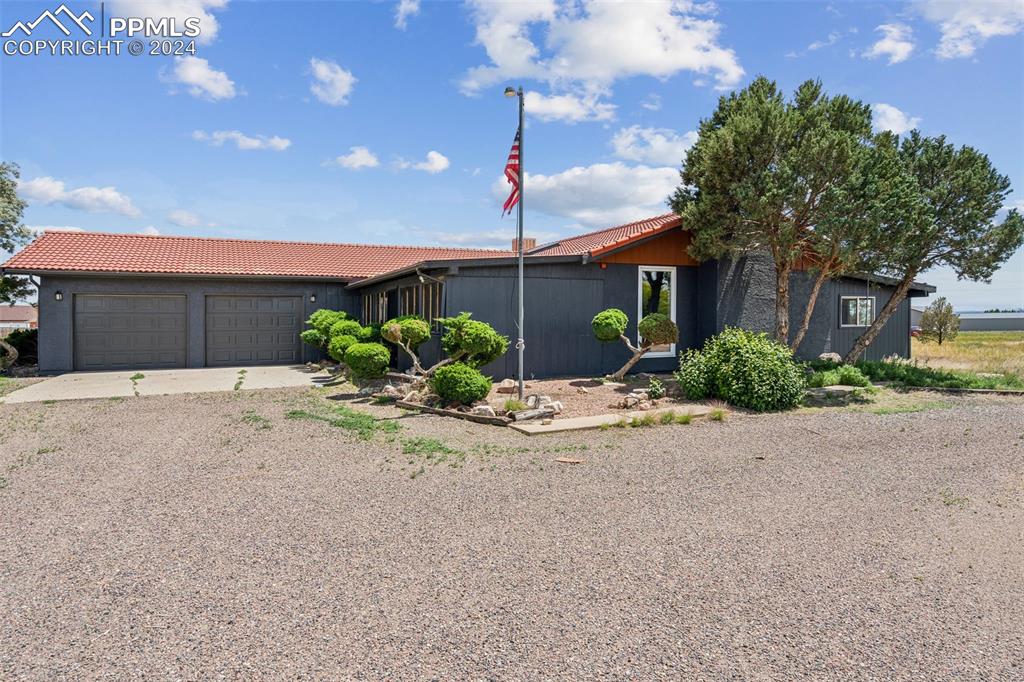 a front view of a house with a yard and potted plants