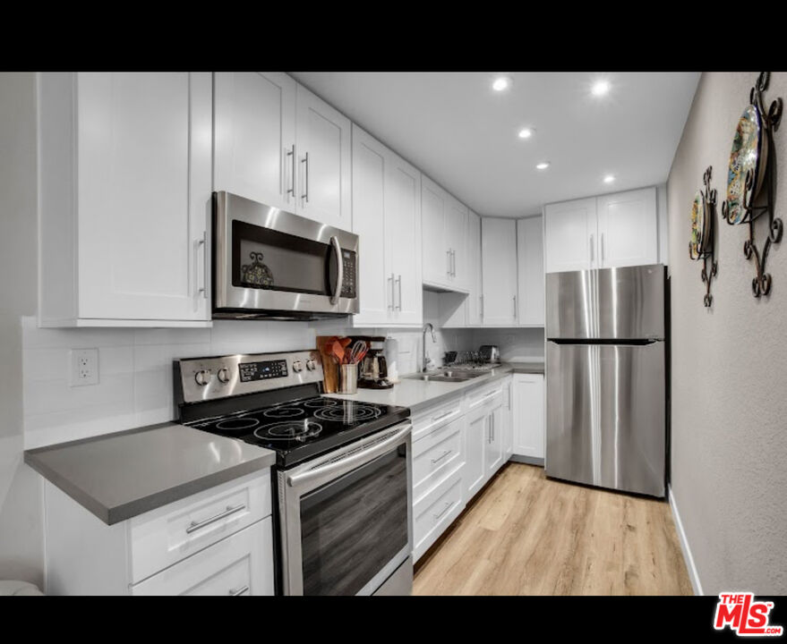 a kitchen with stainless steel appliances granite countertop a refrigerator a stove top oven a sink and dishwasher