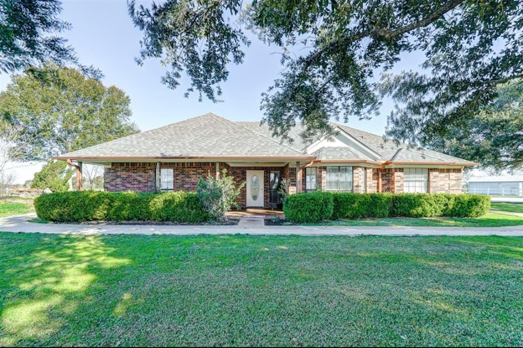 This charming brick home features a spacious front yard with mature trees and a welcoming entrance. Large windows allow plenty of natural light, enhancing its cozy appeal.