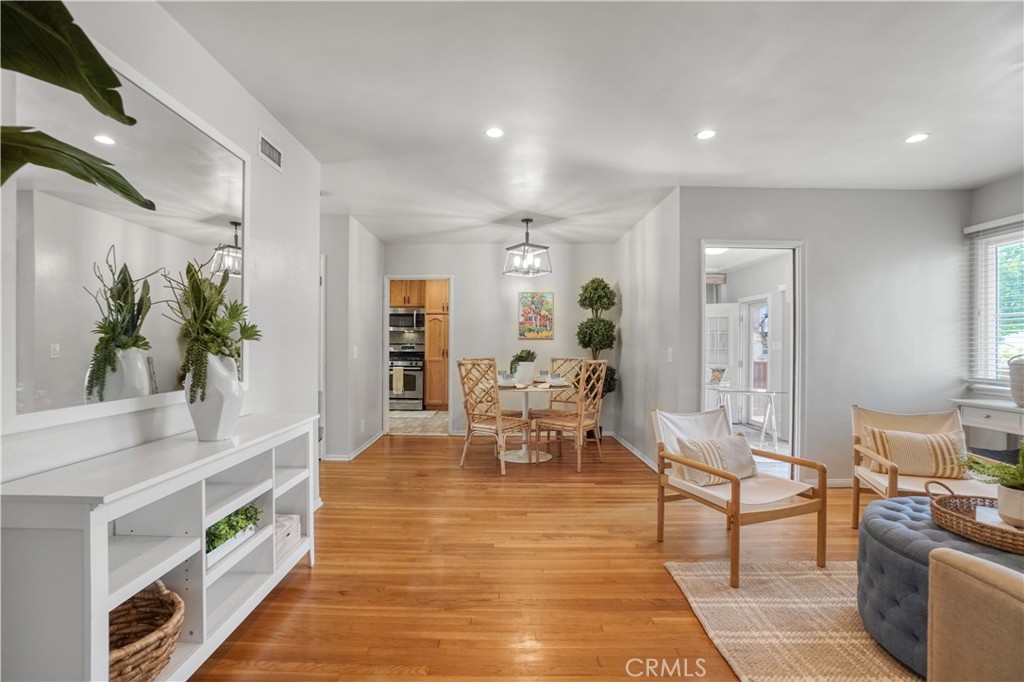 a living room with furniture and a dining table with wooden floor