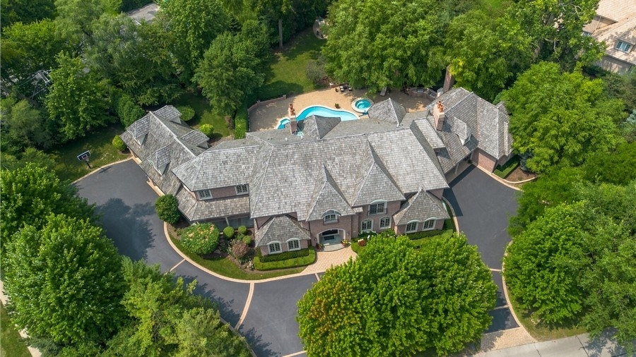 an aerial view of a house with outdoor space and trees all around