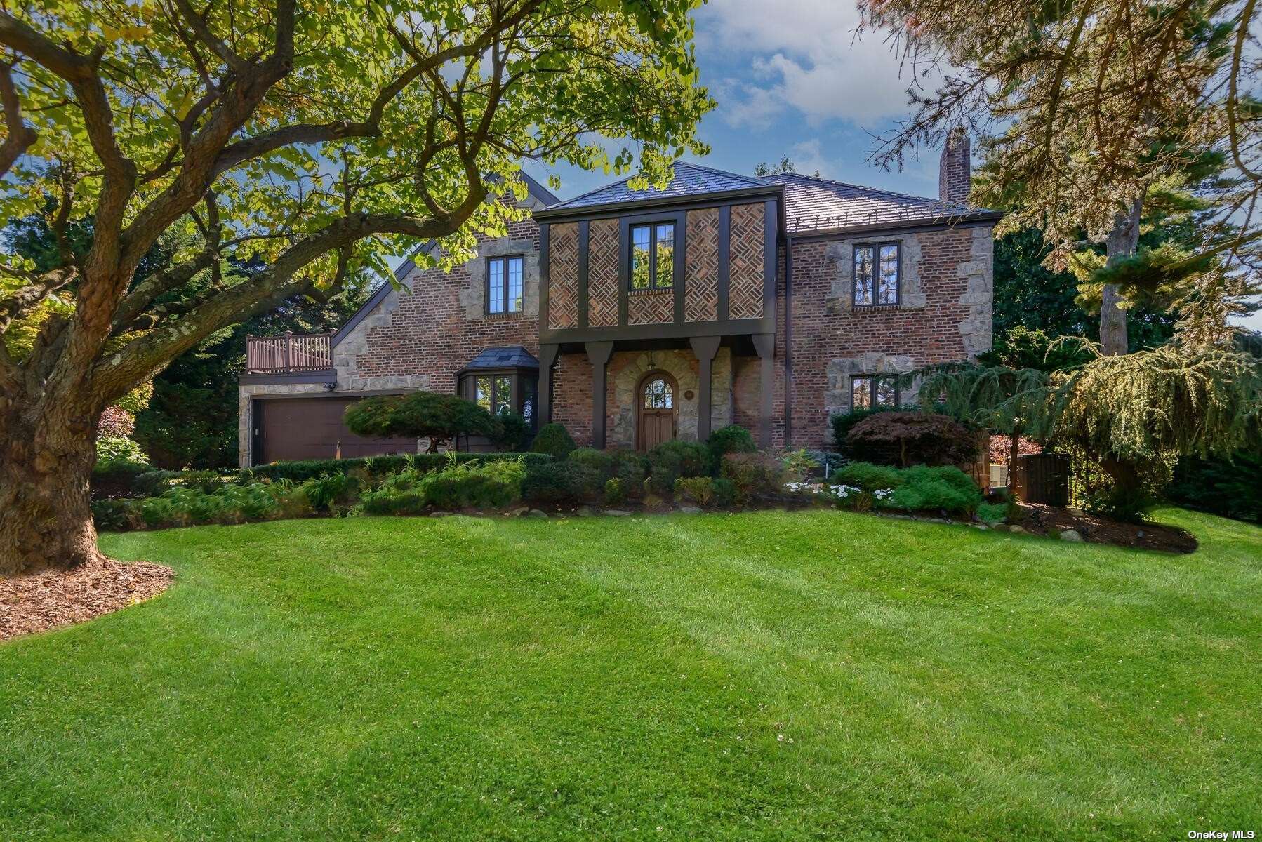 a view of a big brick house with a big yard and large tree