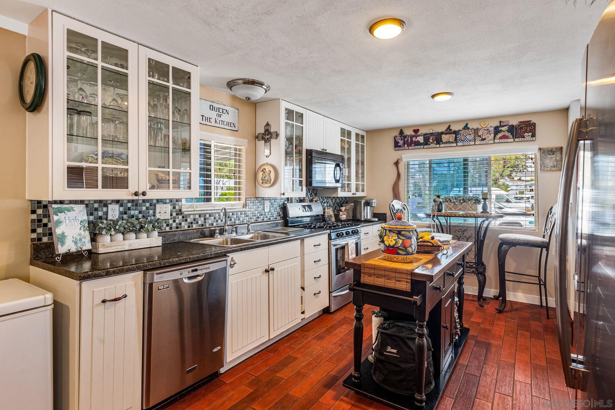 a kitchen with granite countertop a stove a sink and a dining table chair